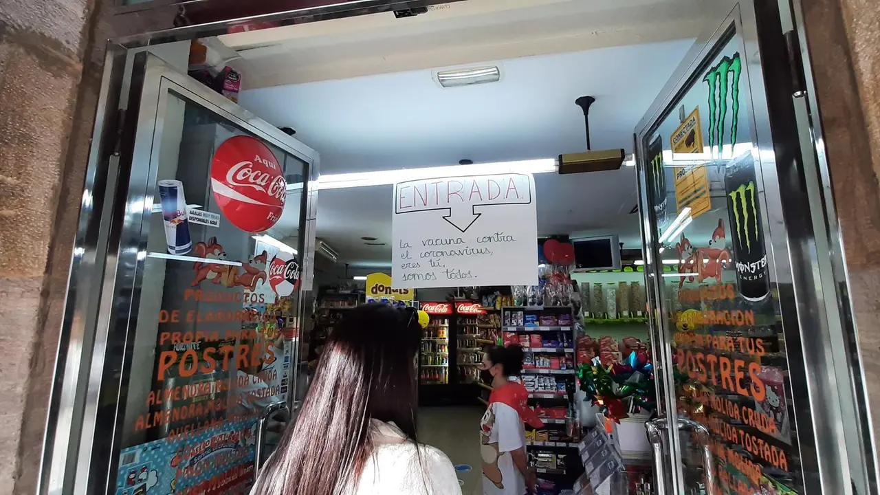 Varias personas esperan su turno para entrar en una tienda de comestibles de Torrelavega. / S. D&iacute;az