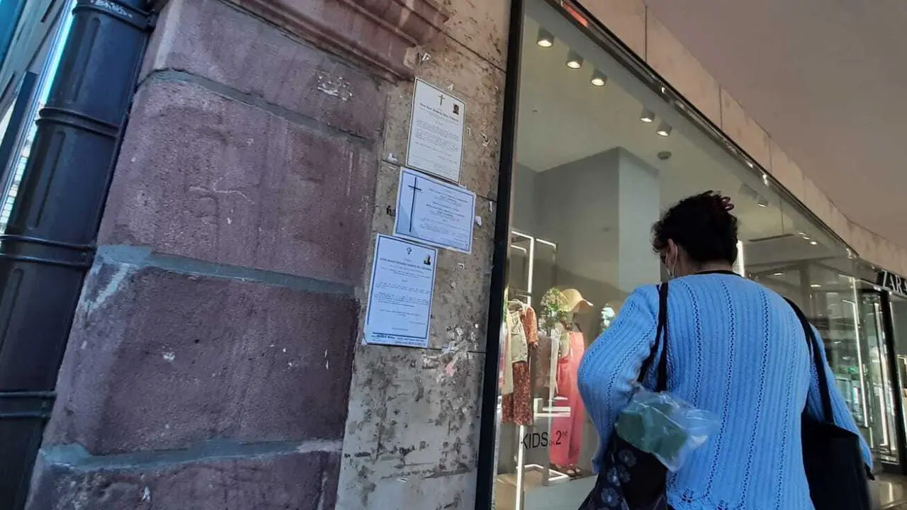 Una persona ojea las esquelas puestas en la pared al lado de la tienda Zara de Torrelavega. / S. D&iacute;az
