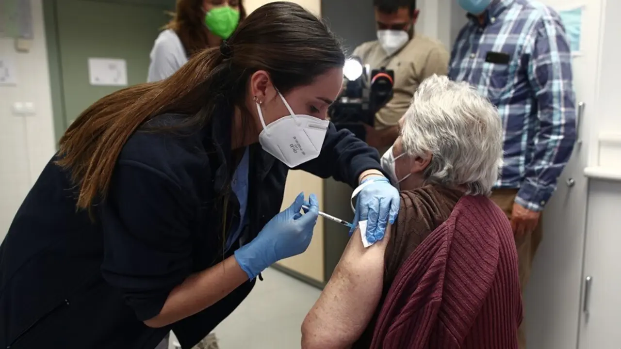 Archivo - Una sanitaria inyecta una dosis de la vacuna de Pfizer contra el coronavirus a una anciana