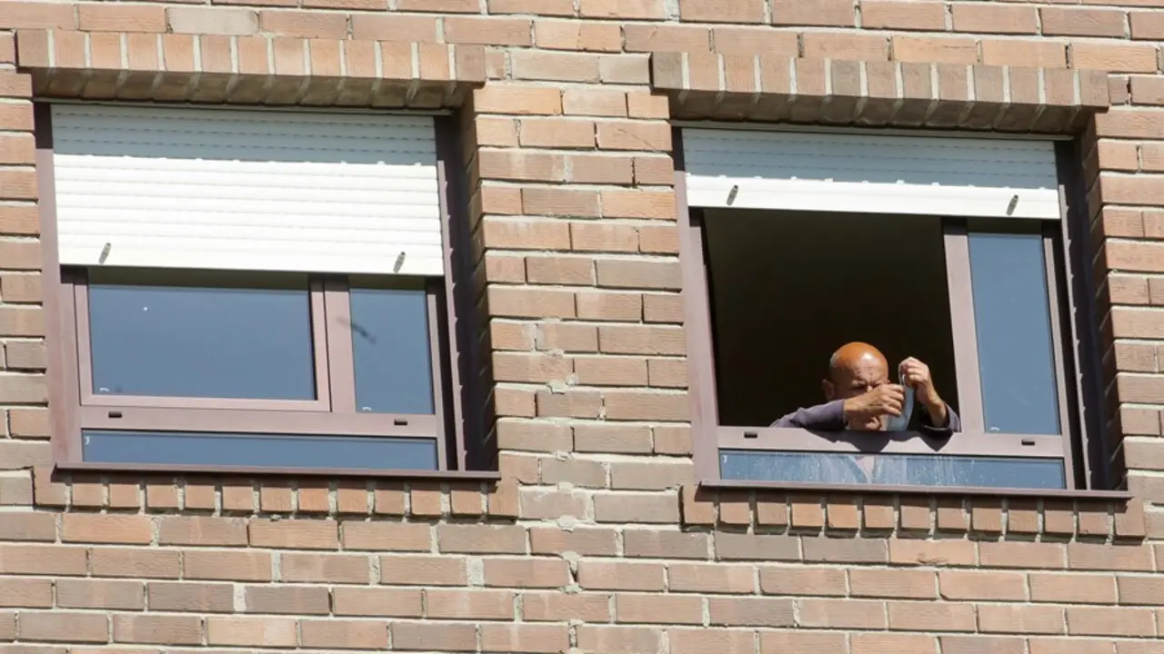 Un anciano coloca su mascarilla en la ventana de su habitaci&oacute;n de la residencia de mayores