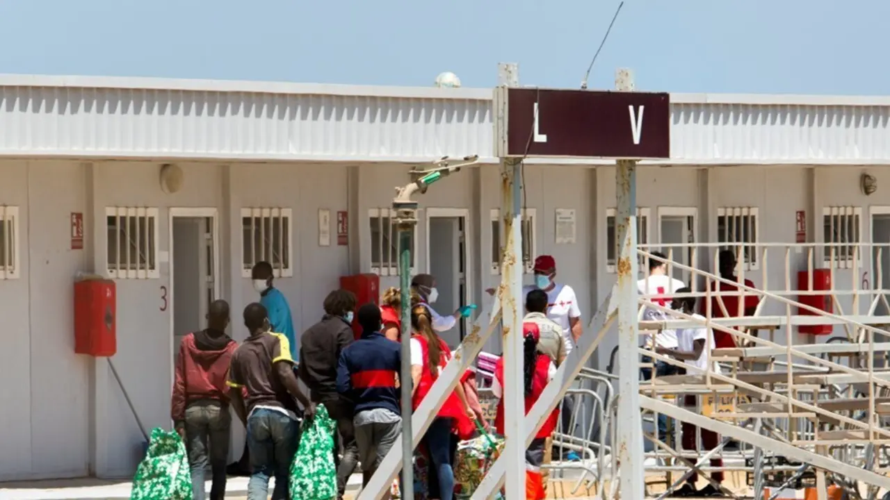 Archivo - Varios migrantes acceden junto a miembros de la Cruz Roja a las instalaciones de la Ciudad del F&uacute;tbol del Altos del Real a 18 de mayo de 2021, en Melilla (Espa&ntilde;a). 