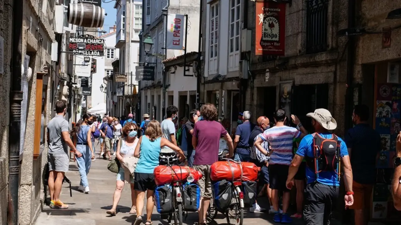 Varios peregrinos caminan con su bicicleta por la Rua do Franco,  en Santiago de Compostela