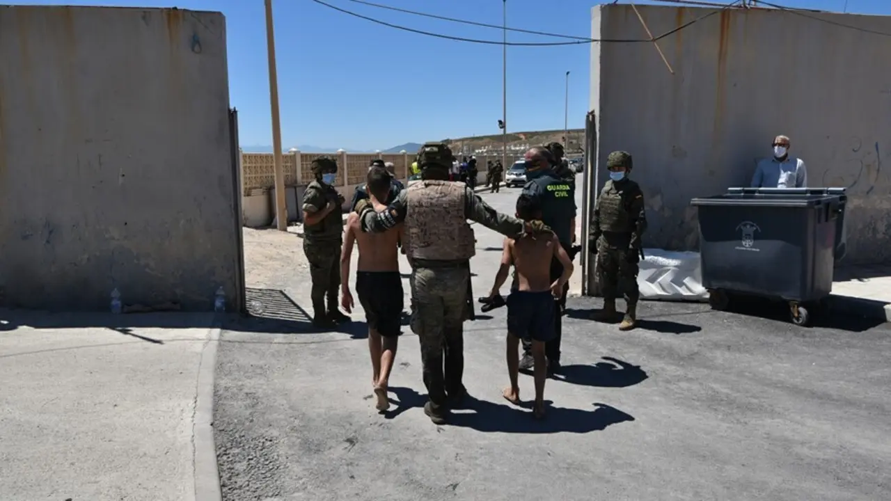 Archivo - Un militar del ej&eacute;rcito espa&ntilde;ol y un agente de la Guardia Civil ayudan a dos menores migrantes procedentes de Marruecos