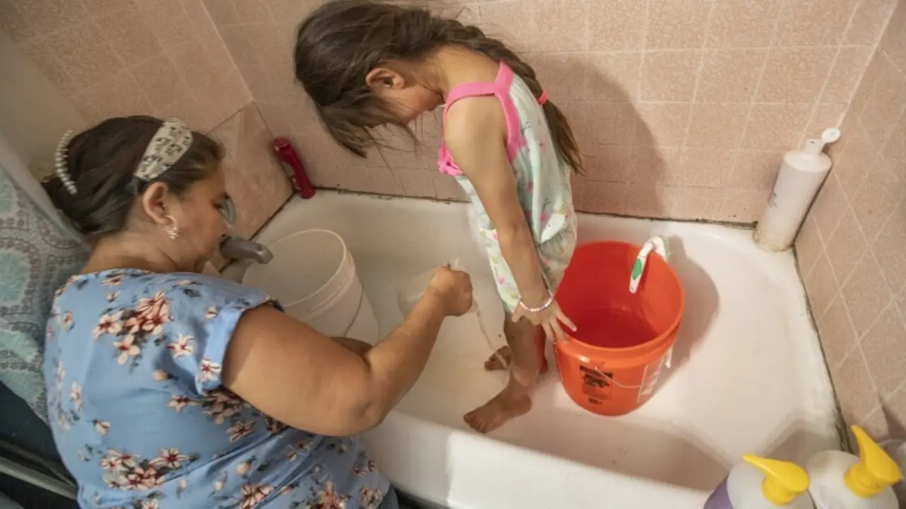 Sandra Sevilla lava los platos con agua de un tanque instalado en el patio trasero de su casa en el condado de Madera. / LA