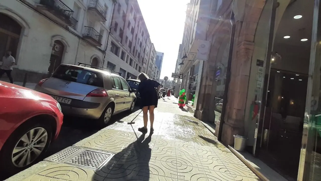 Una persona limpia la acera frente al comercio donde trabaja. / S. D&iacute;az