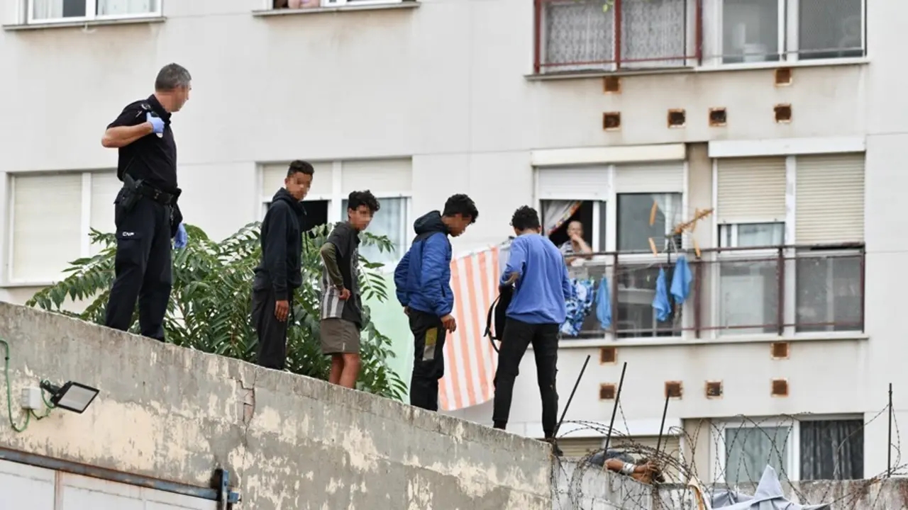 Un polic&iacute;a nacional trabaja para que un grupo de menores migrantes abandone el tejado de una nave industrial en Ceuta