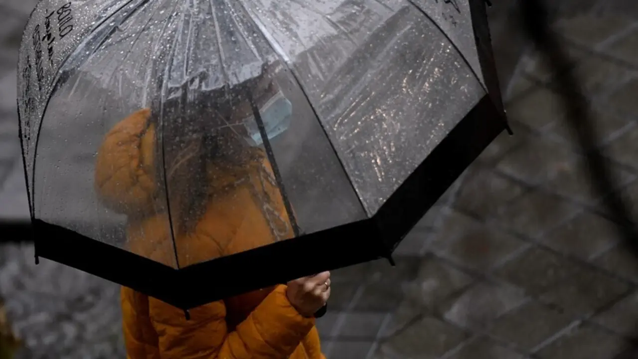 Archivo - Una persona caminando bajo un paraguas para protegerse de la lluvia en Madrid