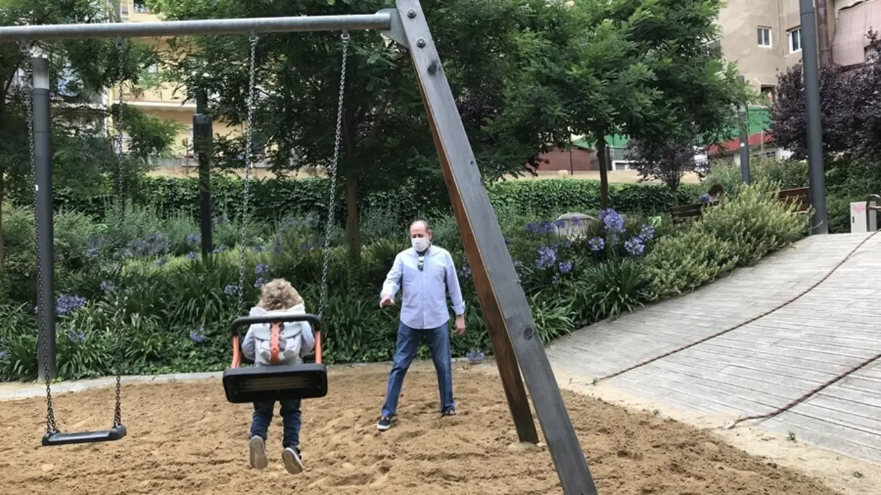 Archivo - Una ni&ntilde;a y su abuelo juegan en los columpios.