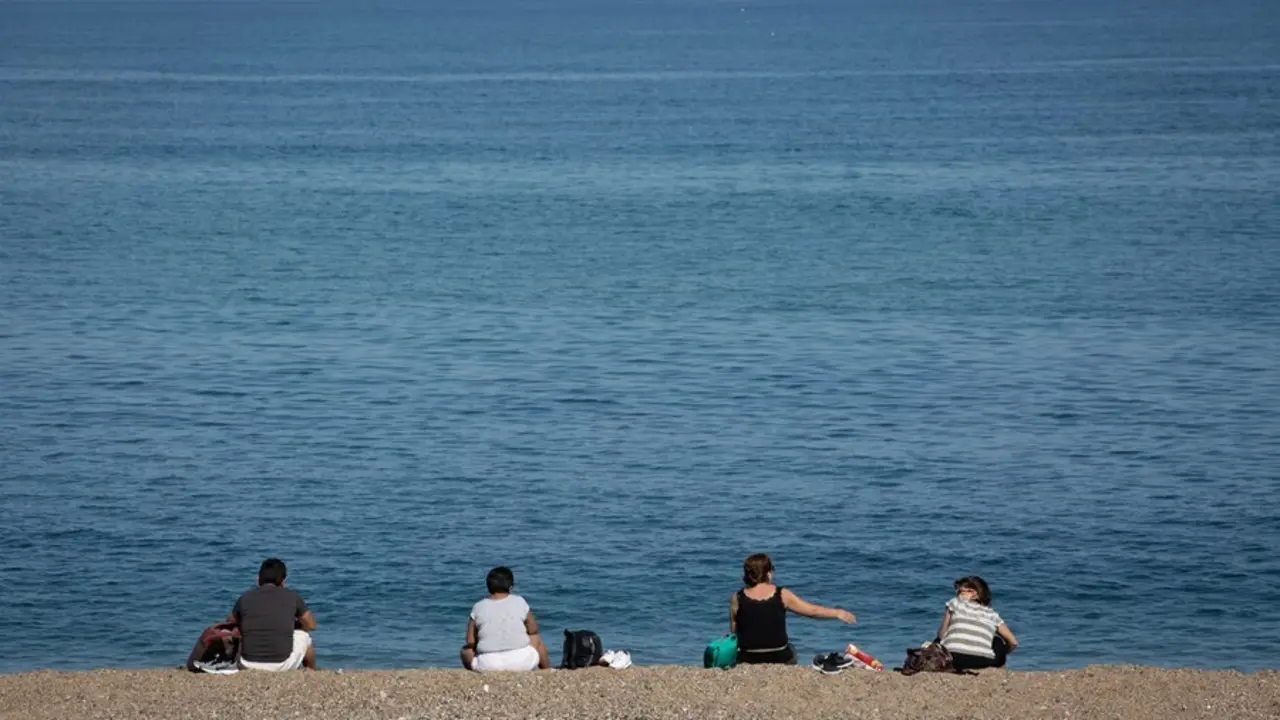 Archivo - Varias personas sentadas en la Playa de la Barceloneta de Barcelona