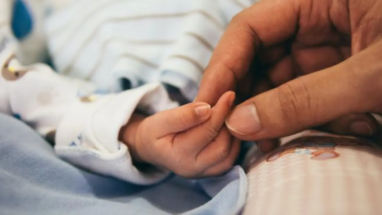 Madre coge la mano de su beb&eacute;.
