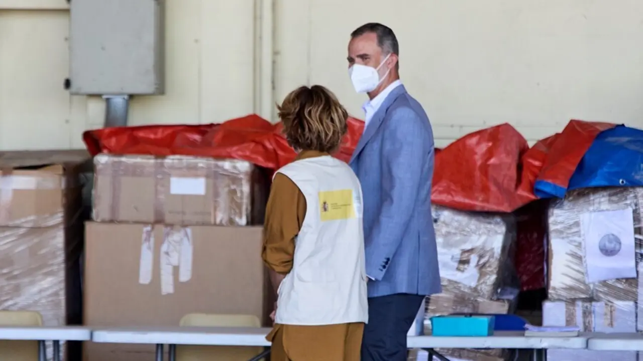 El Rey Felipe VI conversa con una cooperante a su llegada al hangar para visitar el dispositivo provisional en Torrej&oacute;n de Ardoz