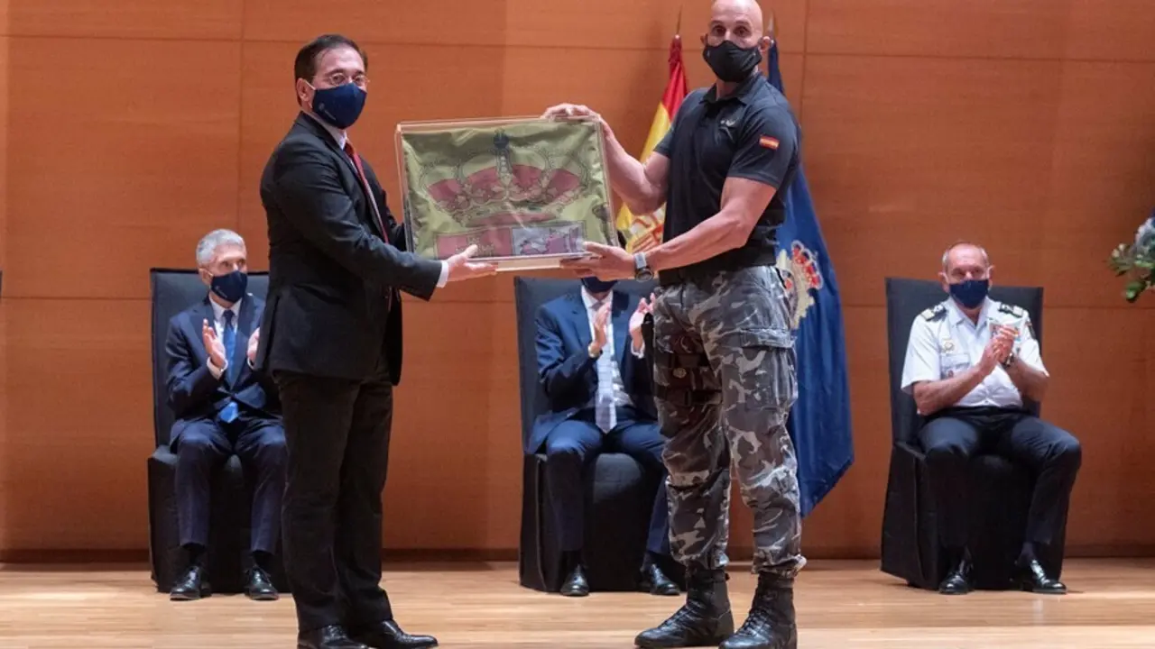 Un polic&iacute;a del Grupo Especial de Operaciones (GEO) entrega al ministro de Asuntos Exteriores, Jos&eacute; Manuel Albares, la bandera nacional que ondeaba en la Embajada de Kabul
