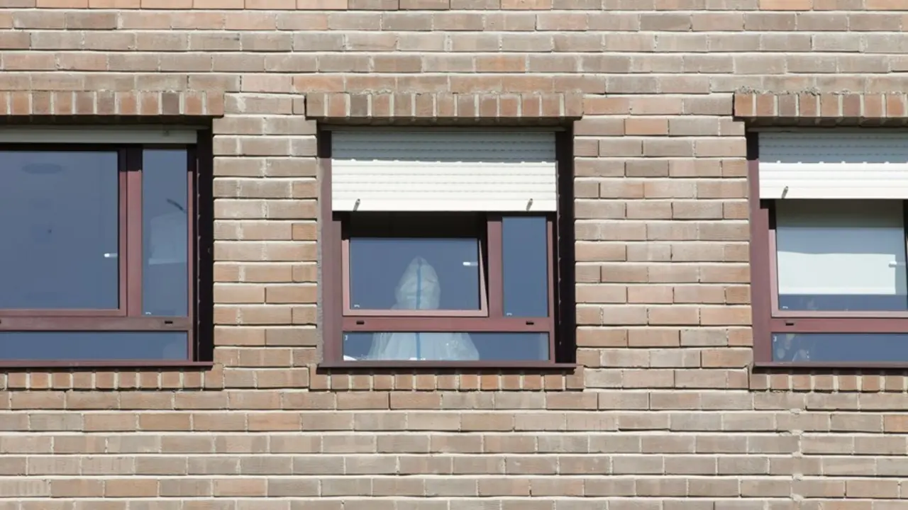Un trabajador sanitario con un EPI, en la ventana de una habitaci&oacute;n de la residencia de Las G&aacute;ndaras, la mayor de Lugo, despu&eacute;s de contabilizar un total de 49 positivos, a 17 de agosto de 2021, en Lugo, Galicia (Espa&ntilde;a). La mayor&iacute;a de los positivos son as
