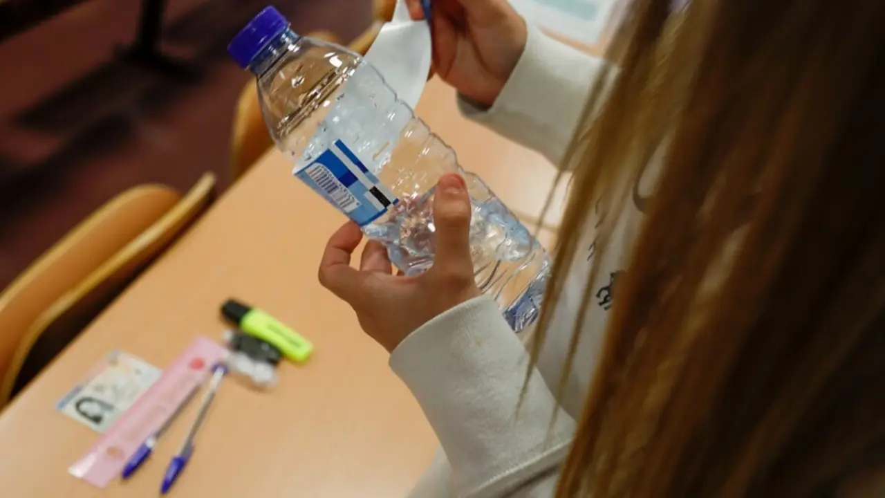 Archivo - Una joven despega el papel de la botella cumpliendo las normas a seguir para la convocatoria extraordinaria de la Evaluaci&oacute;n del Bachillerato para el Acceso a la Universidad (EBAU), a 6 de julio de 2021, en Madrid