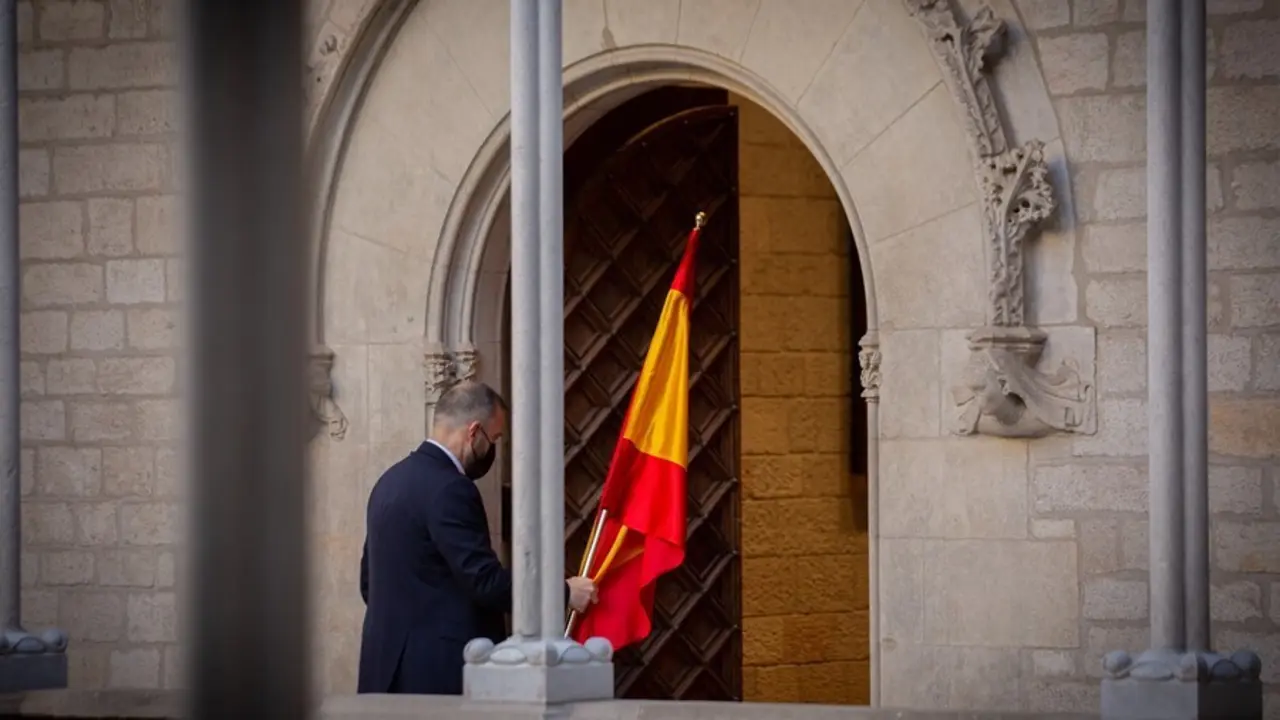 Un hombre retira la bandera de Espa&ntilde;a antes de que el president de la Generalitat comparezca en rueda de prensa en el Palau de la Generalitat