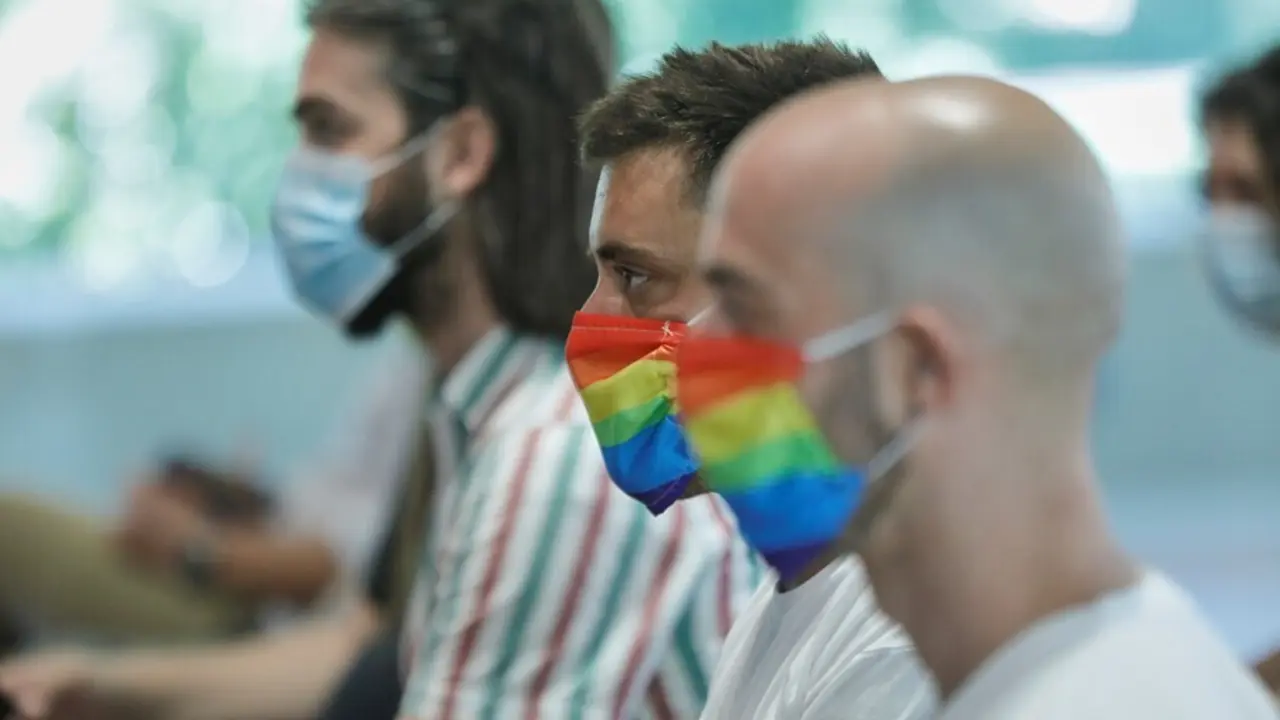 Archivo - Dos hombres se protegen con mascarillas con la bandera LGTB durante su participaci&oacute;n en el acto institucional con motivo del Orgullo 2020, en Madrid (Espa&ntilde;a), a 29 de junio de 2020.