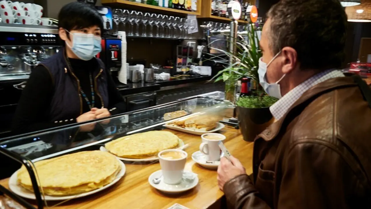 Archivo - Una camarera y un cliente en el interior de un bar