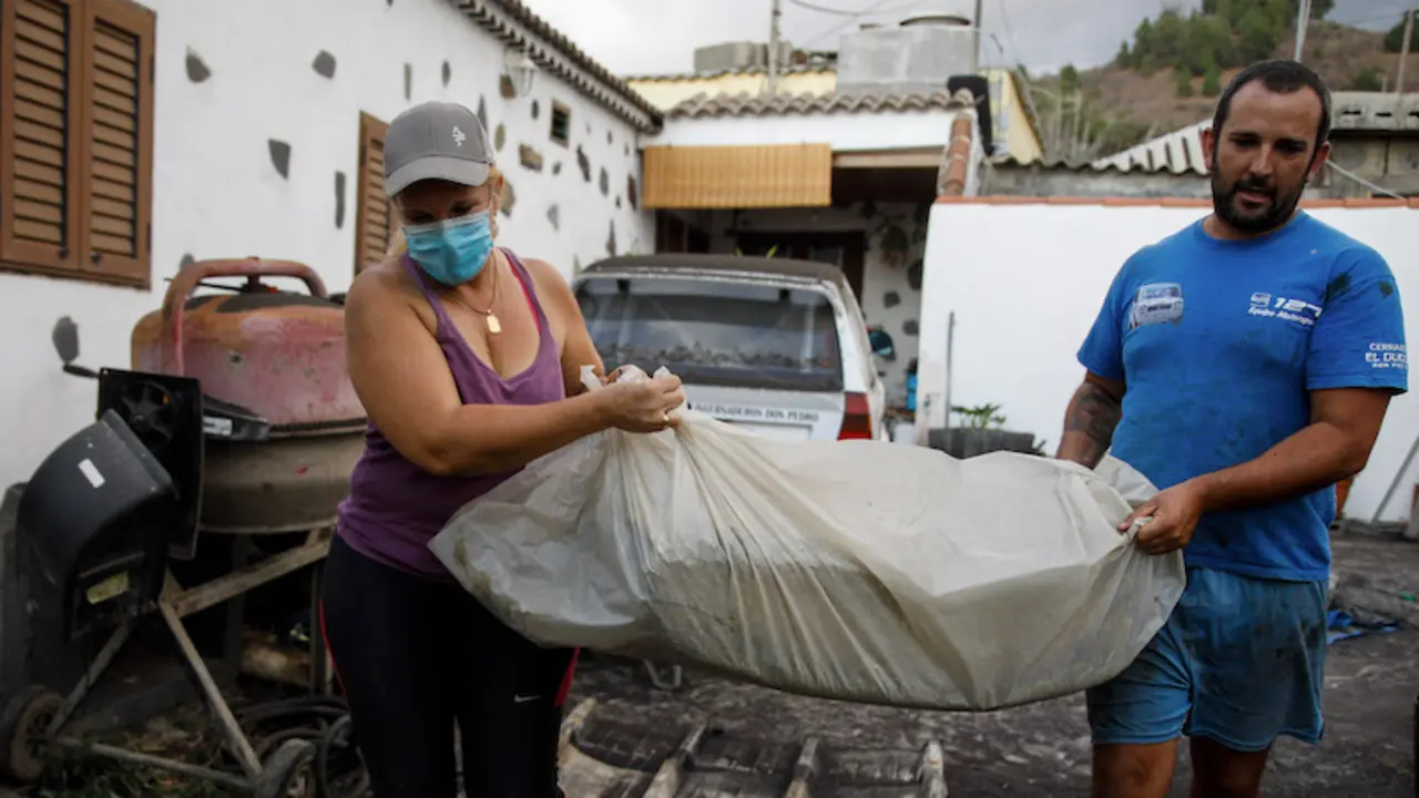 Un hombre y una mujer sacan sus pertenencias de su casa por la actividad del volc&aacute;n de &lsquo;Cumbre Vieja&rsquo;. / Kike Rinc&oacute;n / Europa Press