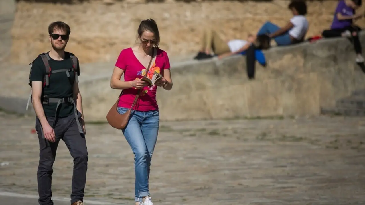 Archivo - Dos personas caminando por Sevilla en un d&iacute;a de subida de temperaturas