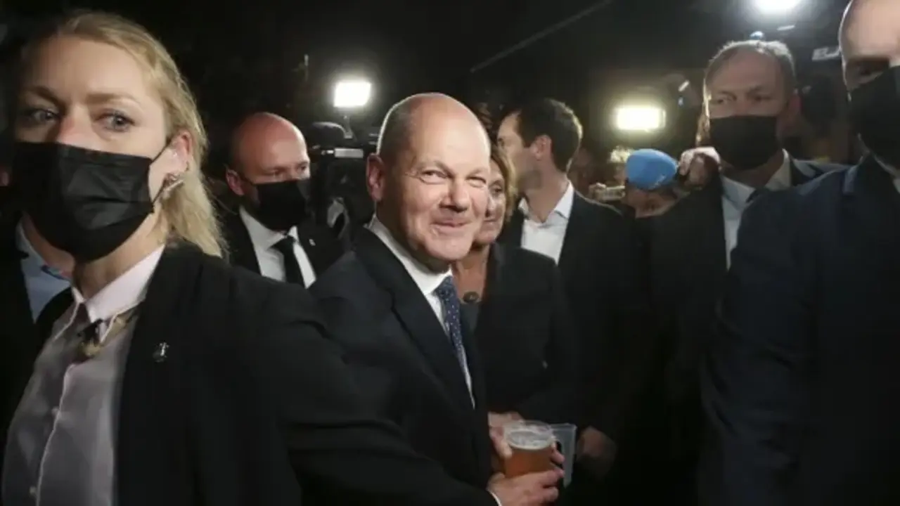 Olaf Scholz (centro) bebe una cerveza al salir de la fiesta electoral en la Casa Willy Brandt de Berl&iacute;n. Fotograf&iacute;a: Wolfgang Kumm/AP