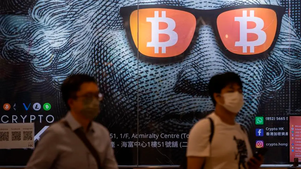 Dos hombres pasan junto a un cartel publicitario de Bitcoins y criptomonedas en Hong Kong, China, el 25 de septiembre de 2021. El 24 de septiembre, China intensific&oacute; la represi&oacute;n de las criptomonedas con una prohibici&oacute;n general de todas las transacciones de criptomonedas, afectando a bitcoin y otras monedas importantes. EFE/EPA/JEROME FAVRE