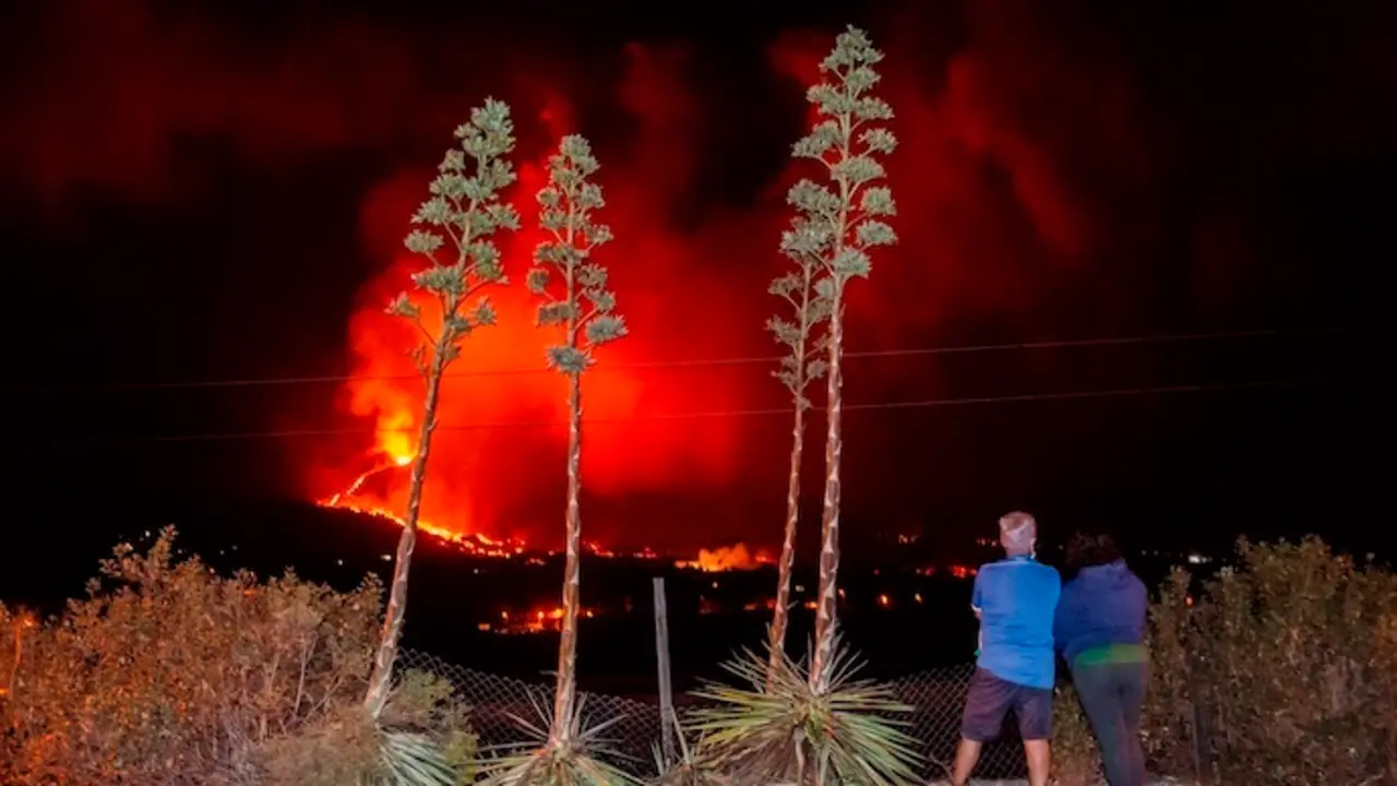 GRAF2426. LOS LLANOS DE ARIADNE (LA PALMA), 14/10/2021.- Una pareja vecinos de Los Llanos de Aridane observan como la colada se adentran en el barrio de La Laguna en la madrugada del jueves. El Plan de Emergencias Volc&aacute;nicas de Canarias (Pevolca) ha determinado una nueva evacuaci&oacute;n por la previsi&oacute;n de avance de la colada de lava del volc&aacute;n de Cumbre Vieja, en La Palma, que discurre m&aacute;s al noroeste y que afecta a entre 250 y 300 vecinos, informaron a Efe fuentes del Gobierno de Canarias. EFE/ Miguel Calero

