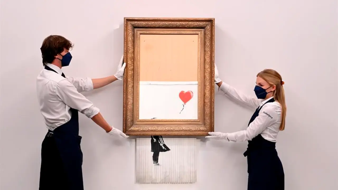Empleados de la galer&iacute;a posan para los fot&oacute;grafos junto a un cuadro titulado "El amor est&aacute; en la papelera" del artista callejero brit&aacute;nico an&oacute;nimo Banksy en la casa de subastas Sotheby's en Londres, Gran Breta&ntilde;a 03 de septiembre de 2021