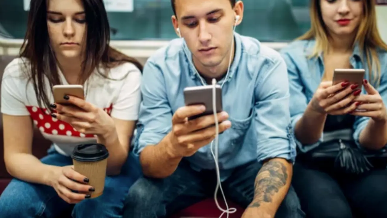 Varios j&oacute;venes con un tel&eacute;fono m&oacute;vil en la mano. / ALERTA