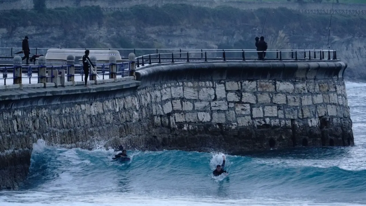 Varios surfistas cabalgan una ola en la playa del Sardinero de Santander. / Hardy