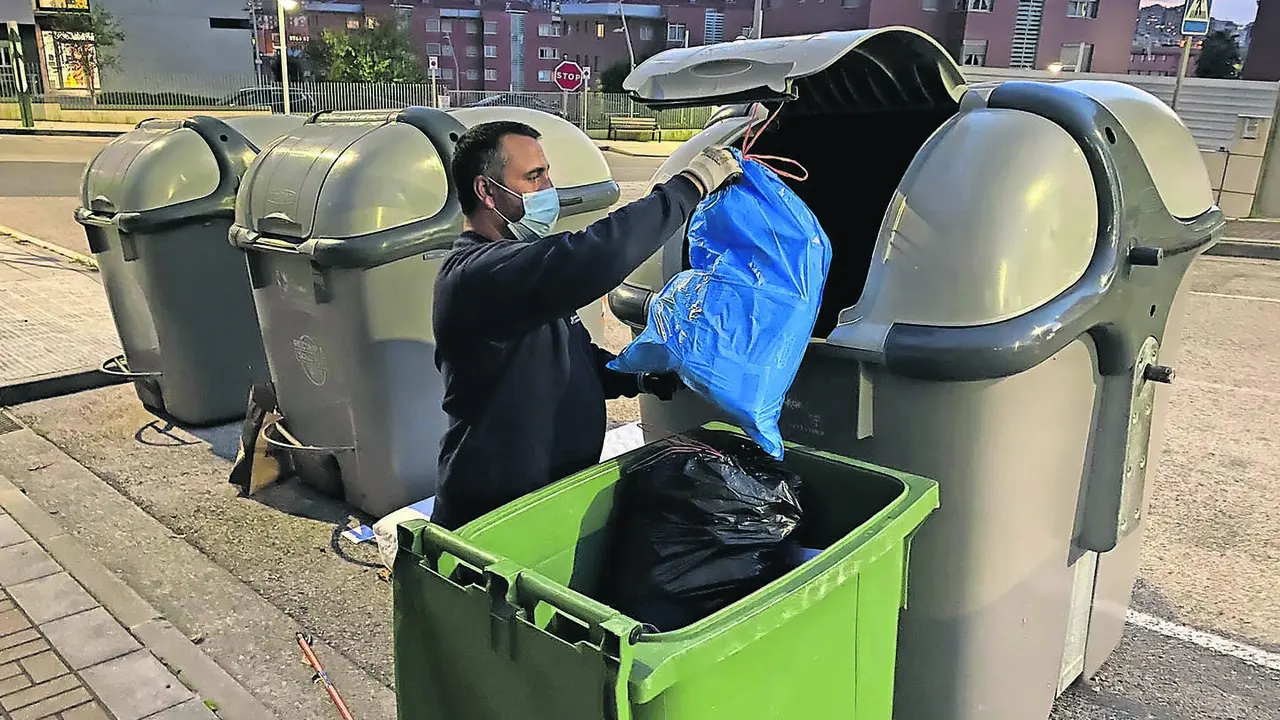 Una persona tira la basura en un d&iacute;a que cambia tras 28 a&ntilde;os el servicios de concesionaria en Santander. / HARDY