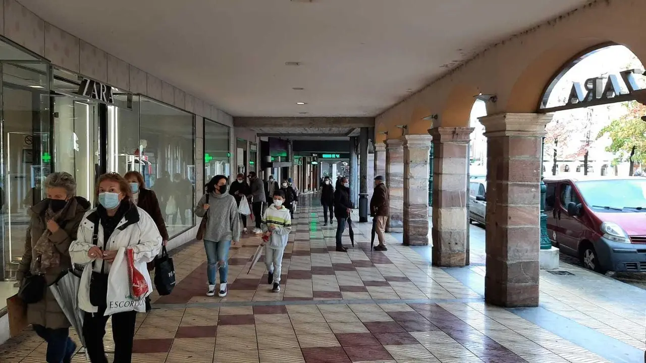 Varias personas pasan delante de la entrada de ZARA en Torralevega.