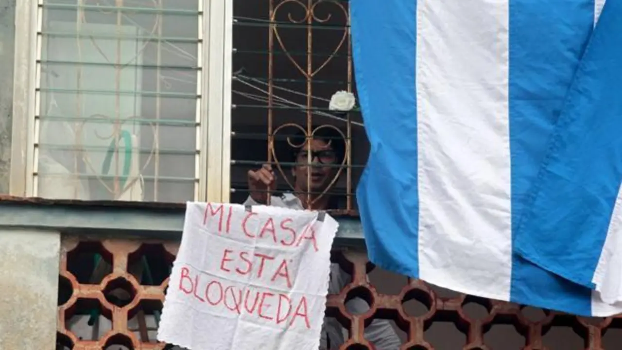 Yunior Garc&iacute;a en su piso con un cartel que dice "Mi casa est&aacute; bloqueada".AFP