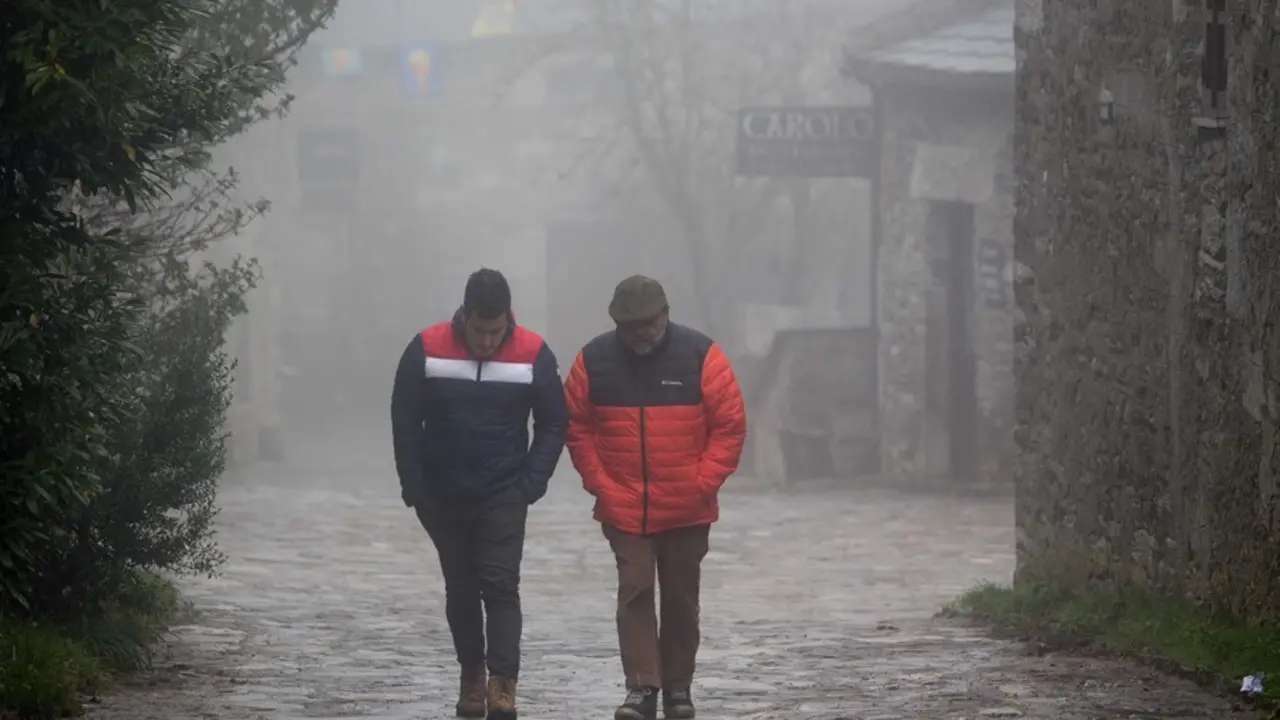 Dos hombres caminan entre la niebla en la aldea prerromana de O Cebreiro, Concello de Pedrafita do Cebreiro, Lugo, Galicia (Espa&ntilde;a).