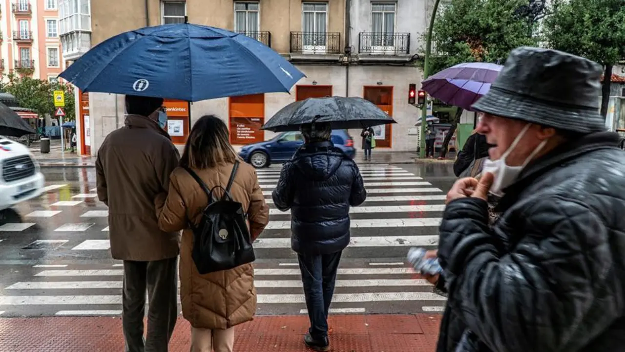 Varias personas con mascarilla y paraguas por la calle Casimiro Sainz de Santander. / EFE/Rom&aacute;n G. Aguilera