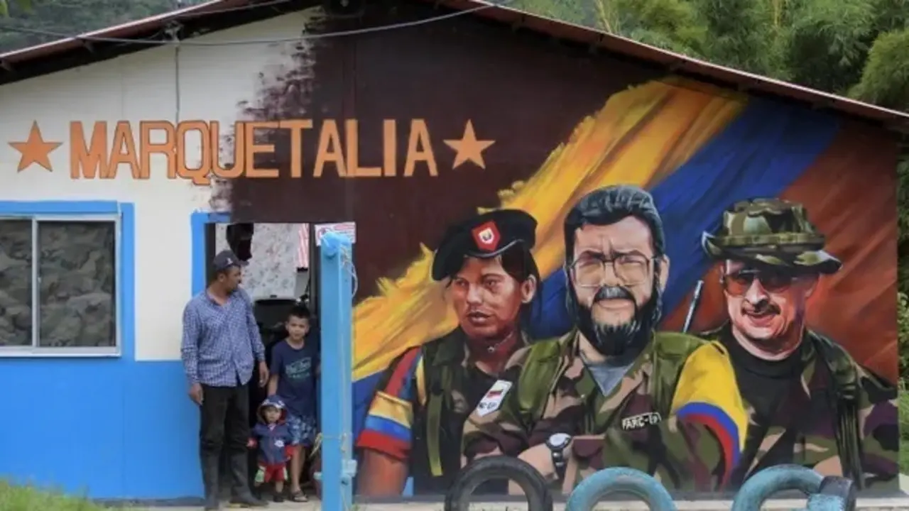 Un hombre y dos ni&ntilde;os junto a un mural del difunto comandante de las Farc Alfonso Cano, en el centro, en Colombia. Fotograf&iacute;a: Ra&uacute;l Arboleda / AFP / Getty Images