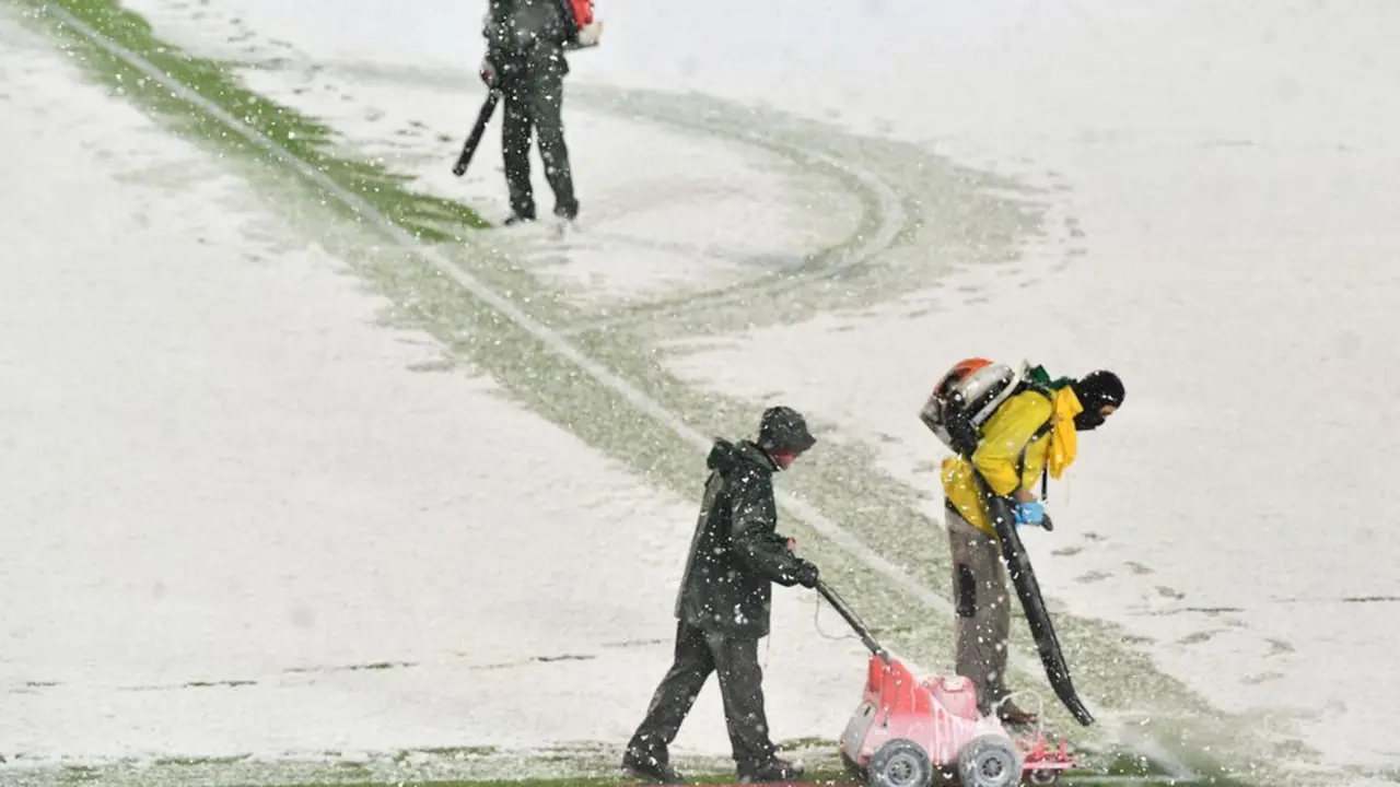 Empleados del Atalanta limpian las rayas del campo y las pintan de rojo para jugar con nieve.
ISABELLA BONOTTO (AFP)