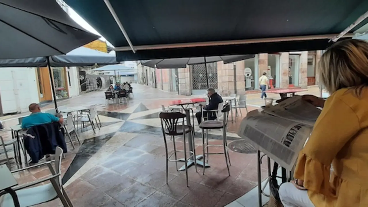 Una persona en un establecimiento de hosteler&iacute;a ojea las p&aacute;ginas del ALERTA en la calle Escalante de Torrelavega.