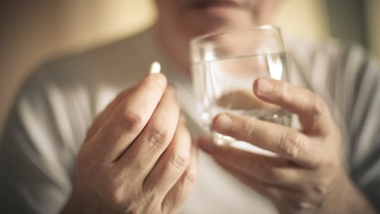 Senior man with pill. Focus is on hand. Close up.