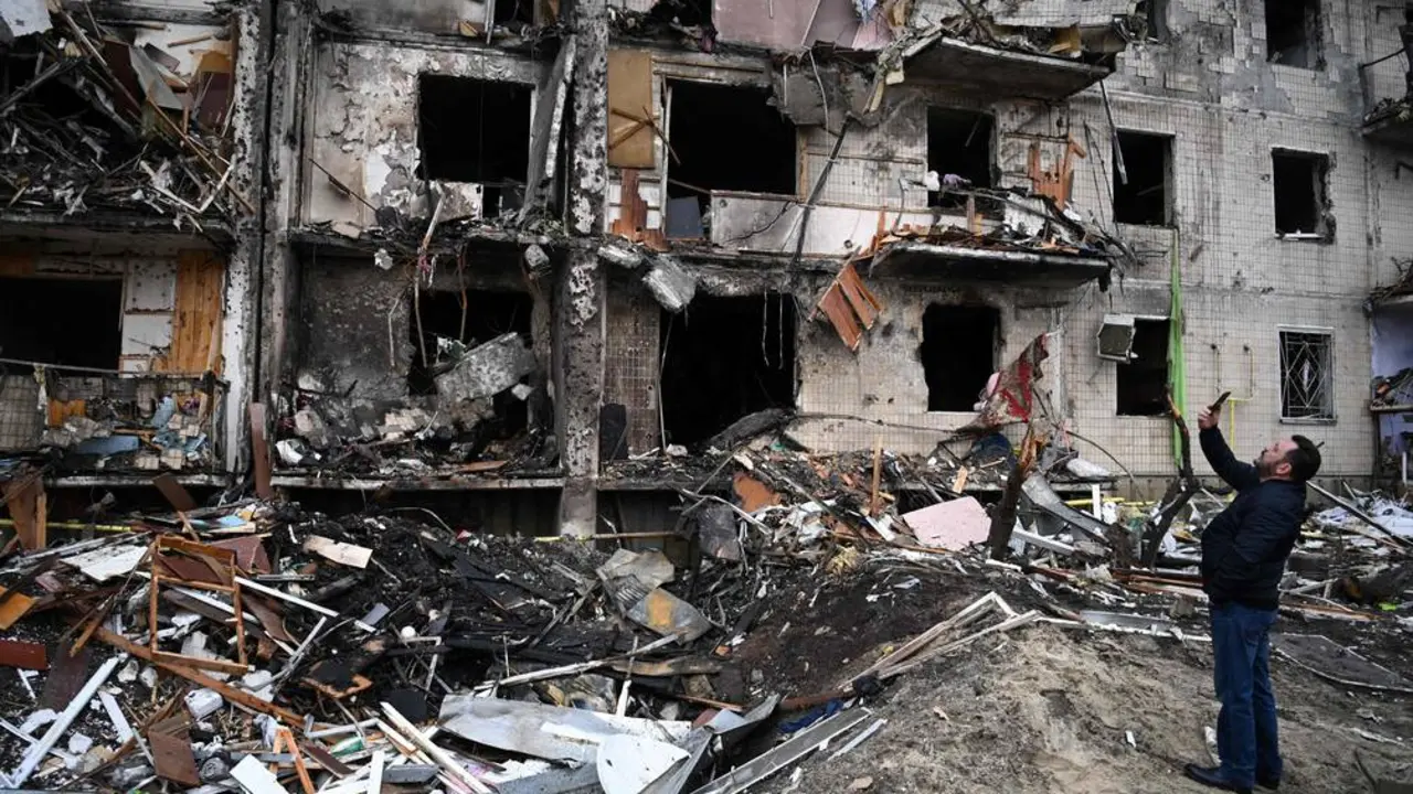 Un ciudadano ucraniano toma fotograf&iacute;as de c&oacute;mo qued&oacute; unas edificaciones ubicadas en la avenida Koshytsa, suburbio de Kiev, luego de los bombardeos rusos. Foto: afp