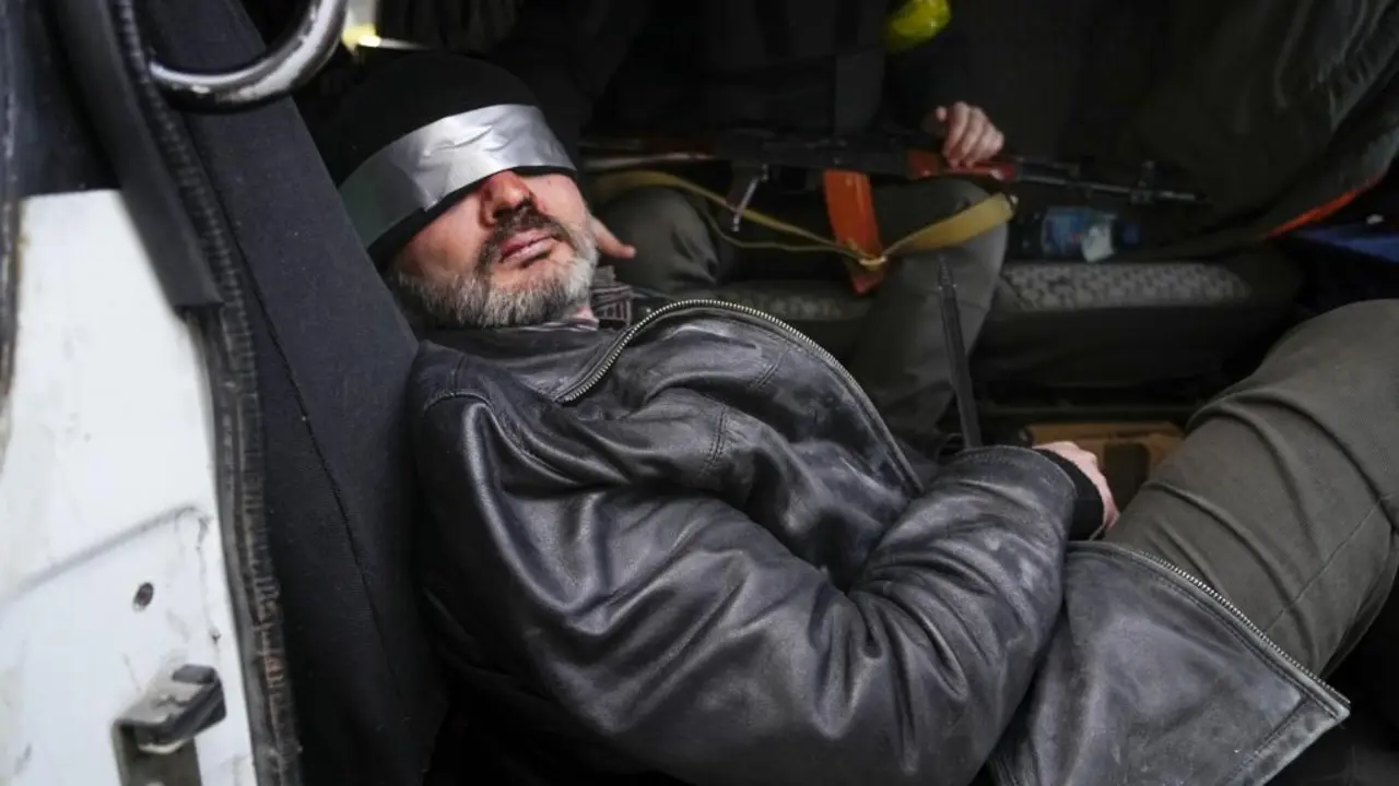 Un presunto agente ruso es mantenido bajo vigilancia armada mientras es escoltado con los ojos vendados en Kiev.  / AP