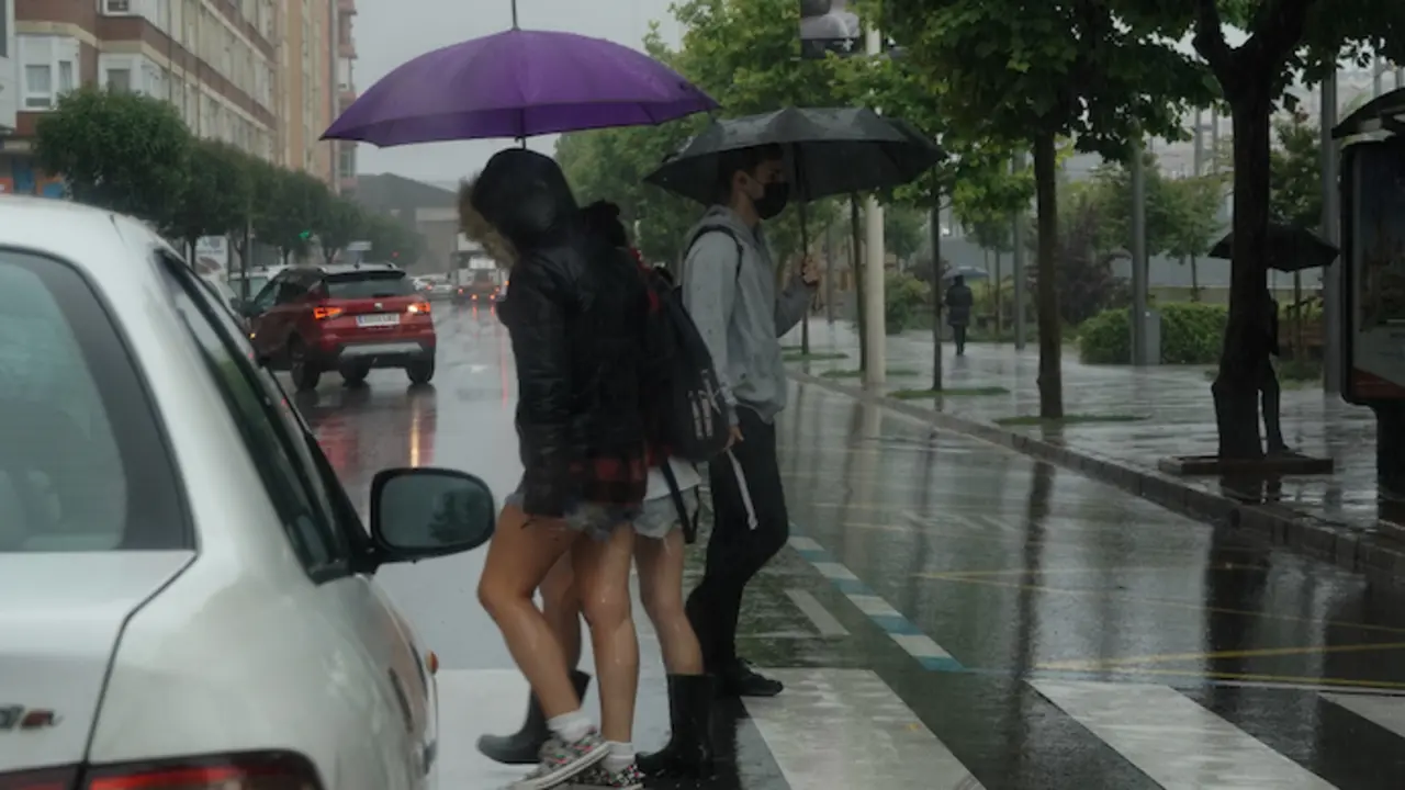 Varias personas caminan bajo la lluvia en las inmediaciones de la estaci&oacute;n de Feve de Santander. / Hardy
