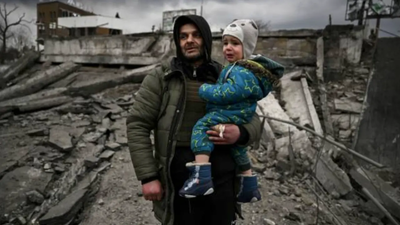 Un hombre sostiene a un ni&ntilde;o mientras huye de la ciudad de Irpin, al oeste de Kiev, el 7 de marzo de 2022. - Las fuerzas rusas bombardearon ciudades ucranianas desde el aire, la tierra y el mar el lunes, con advertencias de que se estaban preparando para un asalto a la capital, Kiev, mientras los civiles aterrorizados no lograron, por segundo d&iacute;a, escapar de la sitiada Mariupol. (Foto de ARIS MESSINIS / AFP)