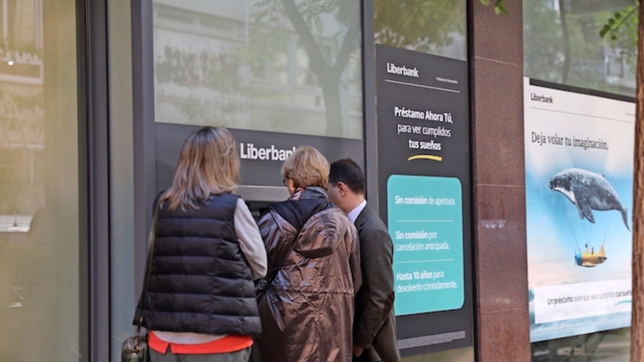 Tres personas efect&uacute;an una operaci&oacute;n en un cajero de una oficina de Liberbank.