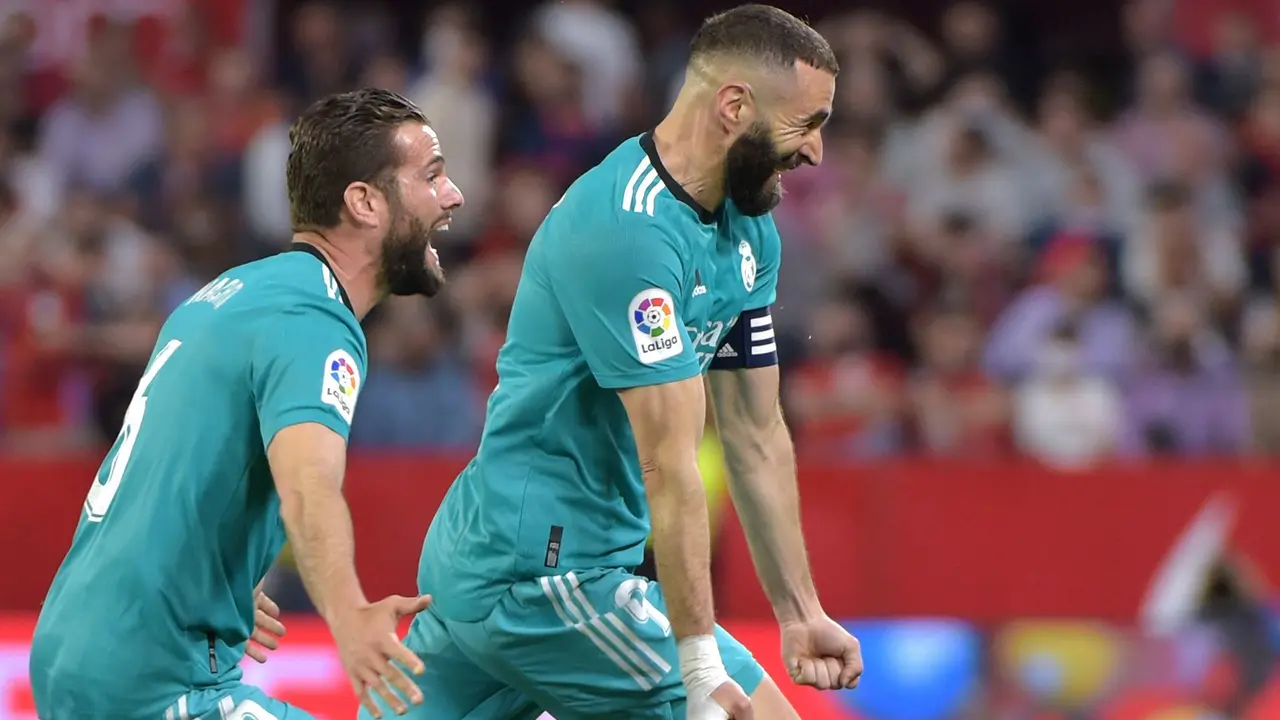 Real Madrid's French forward Karim Benzema (R) celebrates after scoring a goal during the Spanish League football match between Sevilla FC and Real Madrid CF at the Ramon Sanchez Pizjuan stadium in Seville on April 17, 2022. (Photo by CRISTINA QUICLER / AFP)