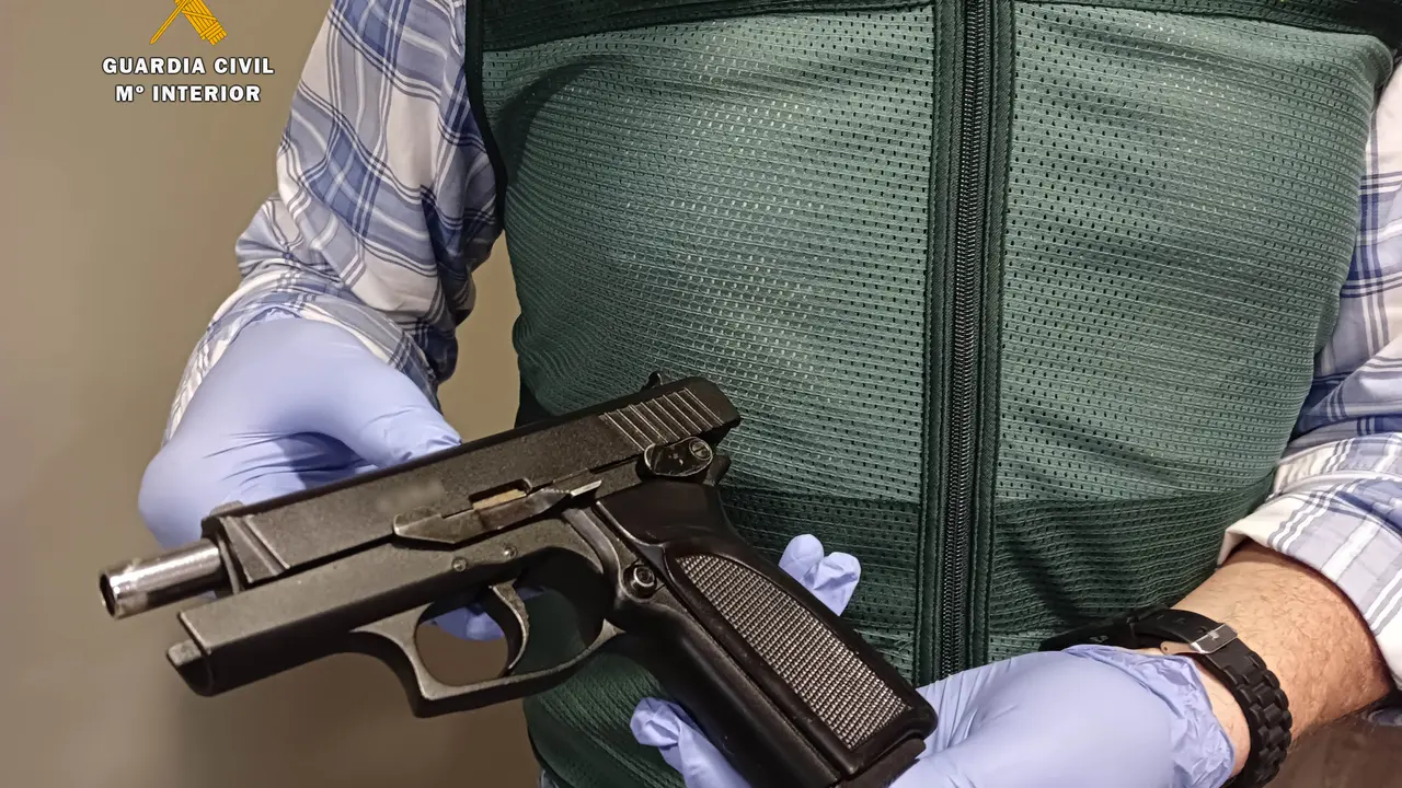 Un Guardia Civil sostiene la pistola incautada al detenido. / OPC