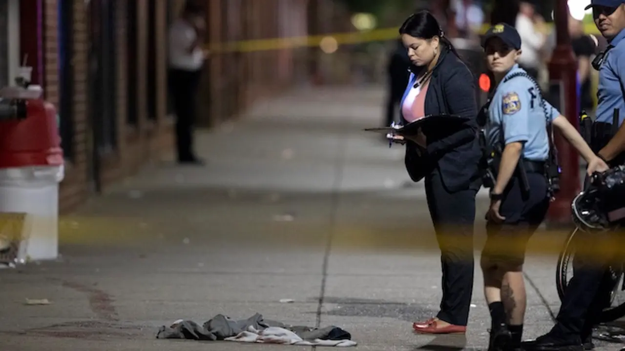 El polic&iacute;a de Filadelfia D. F. Pace examina las pruebas en el lugar de un tiroteo en South Street y sus alrededores que dej&oacute; 3 muertos y 11 heridos el 4 de junio de 2022.