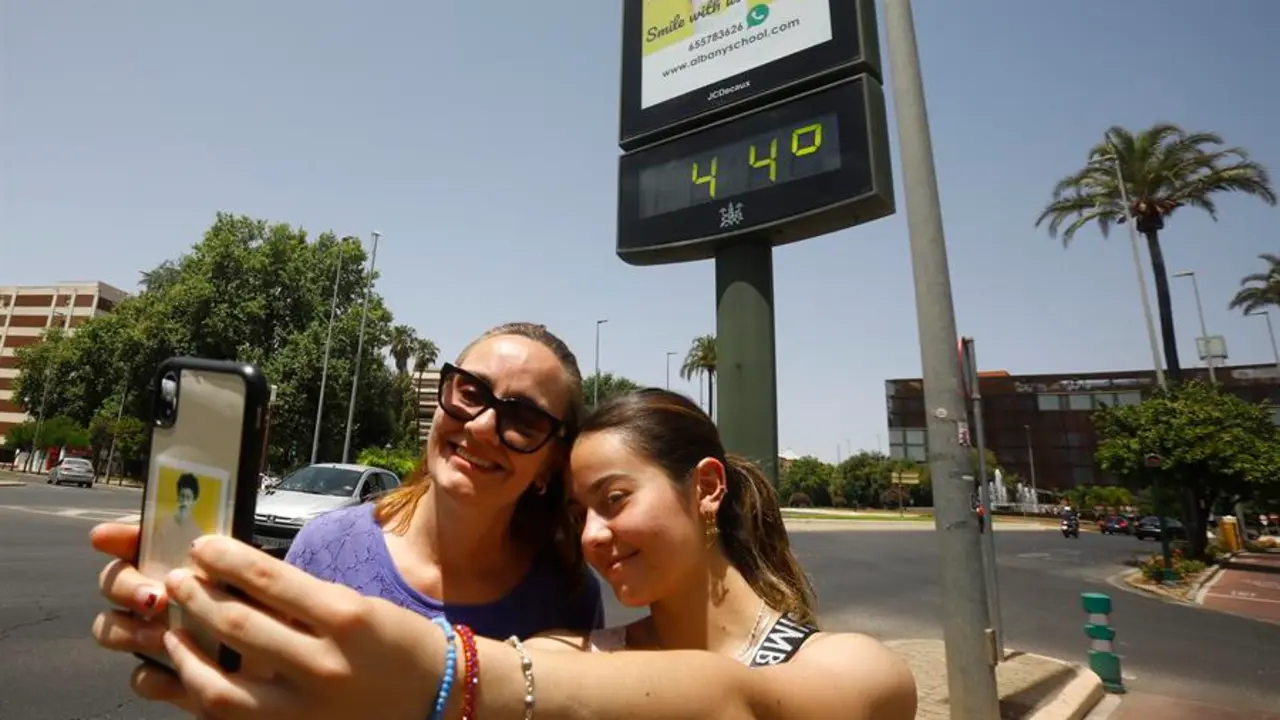 Varios turistas se fotograf&iacute;an junto a un term&oacute;metro que marca 44 grados, este domingo en C&oacute;rdoba. EFE/Salas