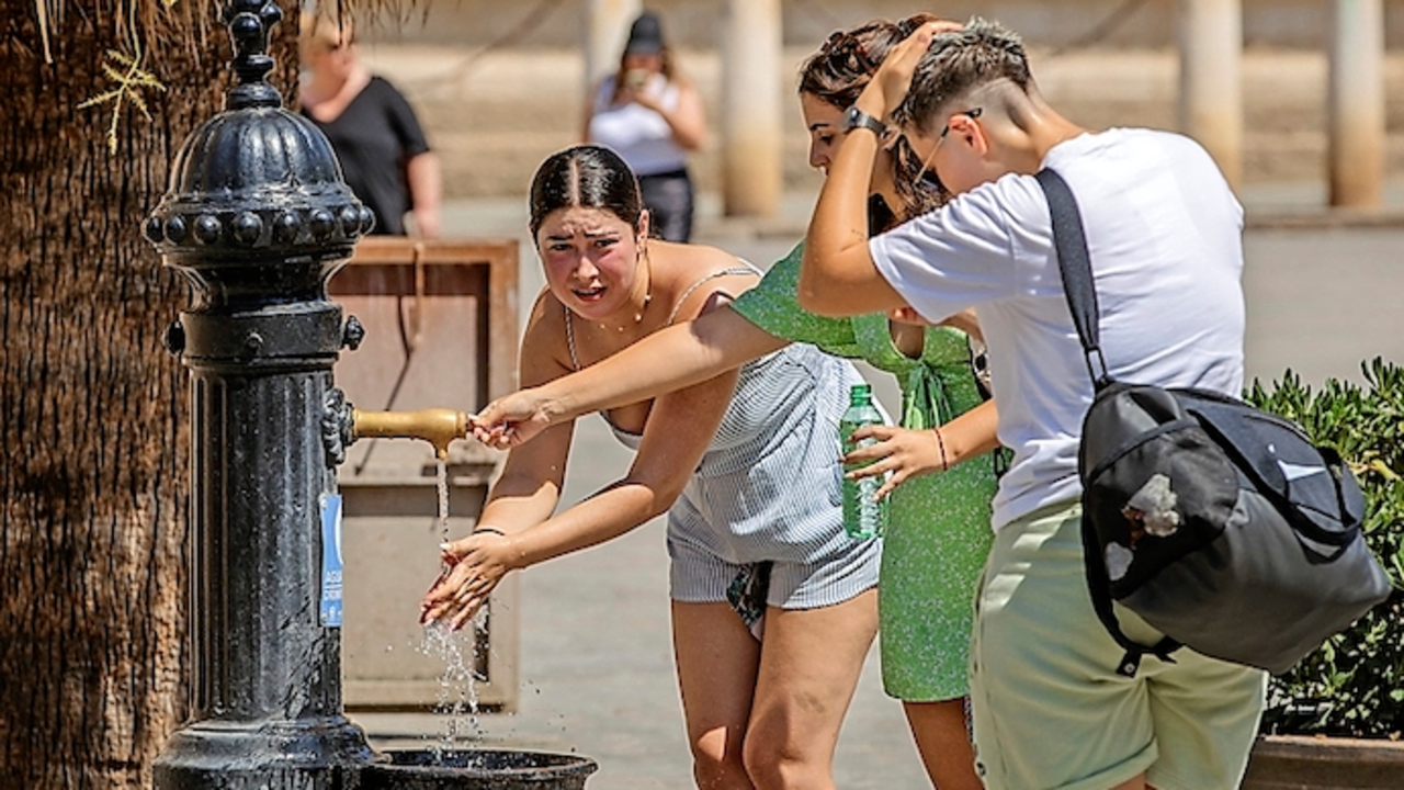 Unas turistas se refrescan en una fuente de agua junto a la Catedral de Sevilla ayer viernes a mediod&iacute;a. / EFE/Julio Mu&ntilde;oz
