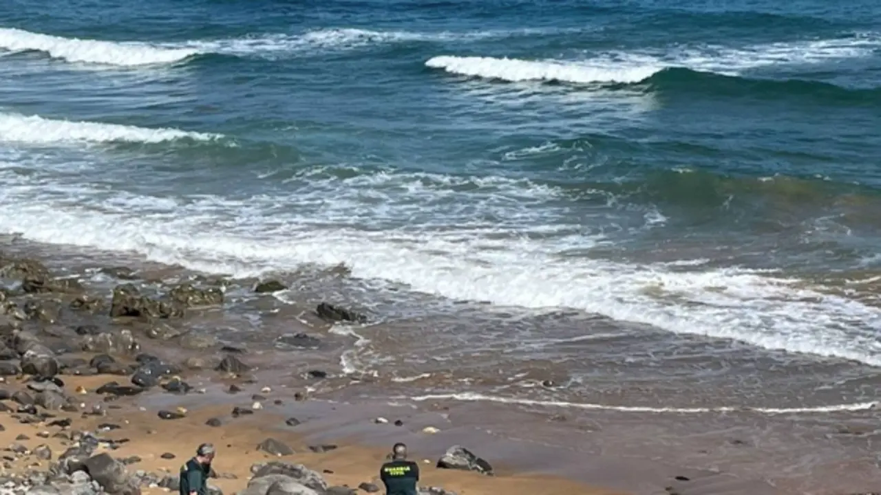 Agentes de la Guardia Civil ante el cuerpo sin vida del buceador aparecido en una playa de Caravia. / GUARDIA CIVIL