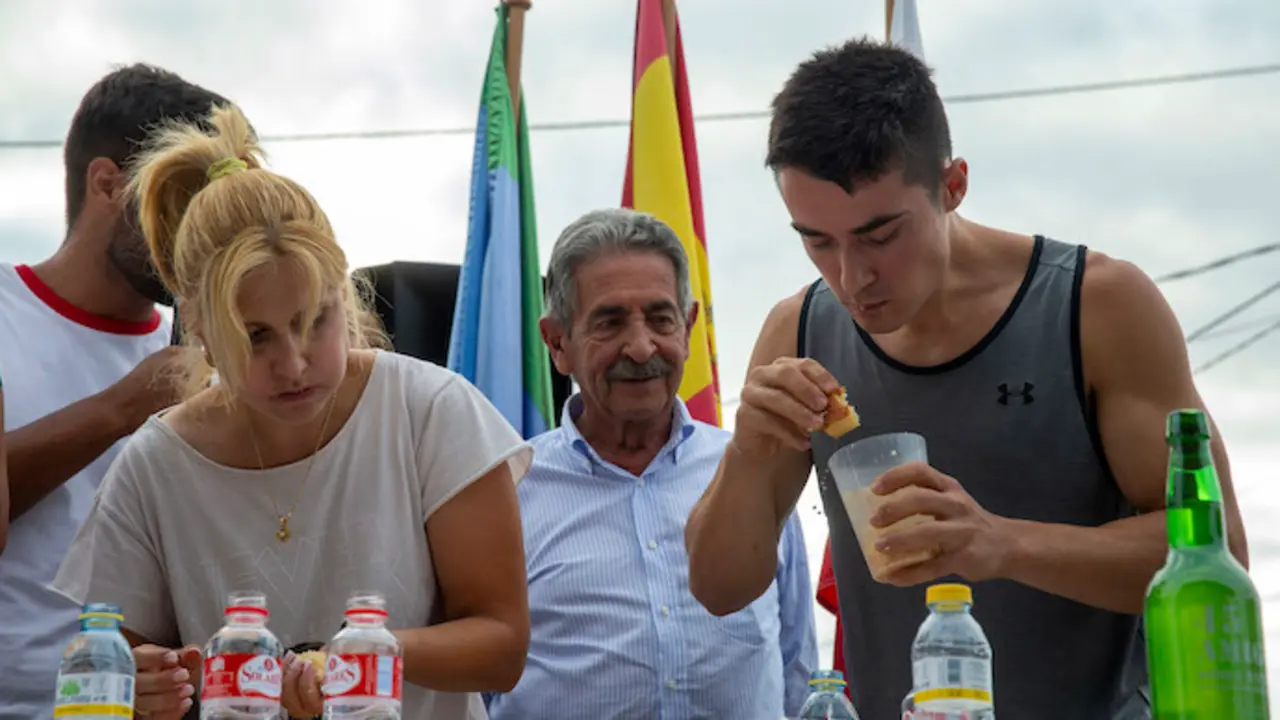 El presidente de Cantabria, Miguel &Aacute;ngel Revilla, mira entusiasmado como engullen sobaos los concursantes el 27 de julio de 2022. / ALERTA